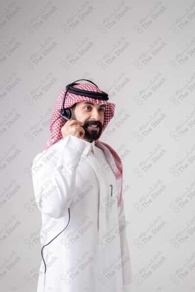 بورتريه رجل سعودي يلبس سماعة الرأس ويقوم بالتواصل عبر السماعة - خدمة العملاء ، مكالمة هاتفية