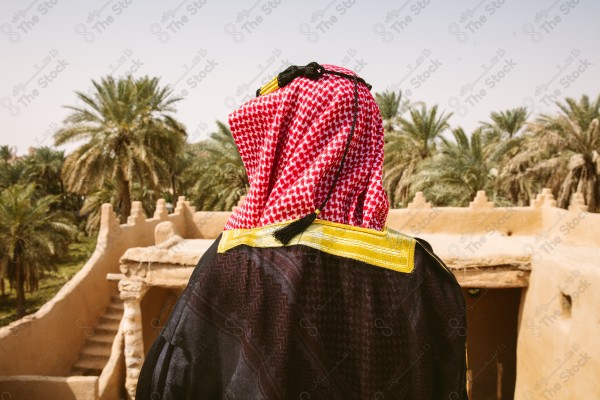 لقطة لرجل سعودي يرتدي الزي التراثي الشعبي في يوم التأسيس يقف فوق مبنى طيني, الزي التراثي, يوم التأسيس, مباني أثريه قديمه.