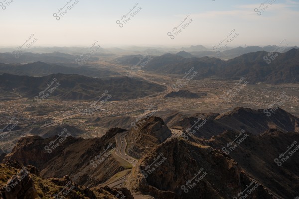 A mountainous view of a winding road passing through the mountains in a vast natural area under a clear sky.