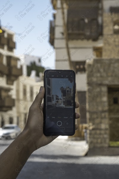 A snapshot of the ancient buildings in the historic country in Jeddah, Saudi Arabia, showing a man holding the phone, the streets of the historic country in Jeddah, historical monuments in Jeddah, tourism in Saudi Arabia.