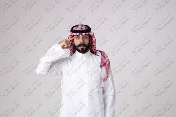 بورتريه رجل سعودي يقف على خلفية بيضاء ويشير بيده اتجاه معين