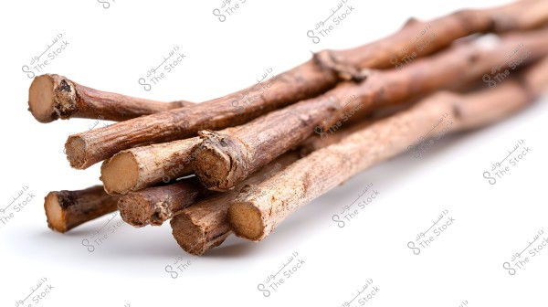 A collection of brown miswak sticks placed on a white surface. The sticks are clearly visible with a rough texture on their natural surface.