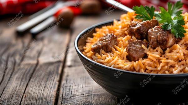 Image of a dish of cooked Basmati rice with beef pieces, garnished with some green parsley leaves. The rice is served in a dark-colored bowl on a wooden table, with blurred cutlery visible in the corner.