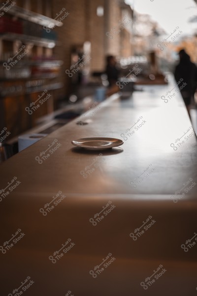 صحن فارغ موضوع على طاولة في مقهى بإنارة خافتة في الخلفية.
