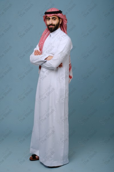 Portrait of a Saudi young man wearing the Saudi dress, and happiness and joy appearing on his features, against a heavenly background