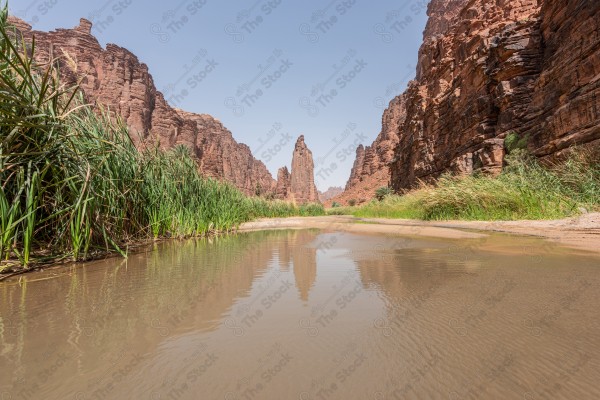 لقطة جوية لسلسلة من الجبال الصخرية في وادي الديسة بتبوك في السعودية وتظهر السماء صافية نهارًا، صخور وجبال.