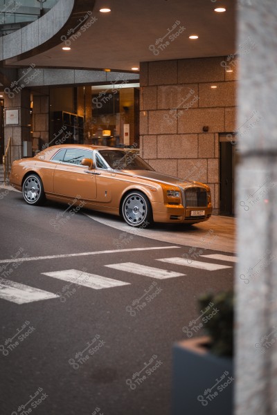 سيارة فاخرة بلون ذهبي متوقفة أمام مدخل فندق مميز بجدران حجرية.