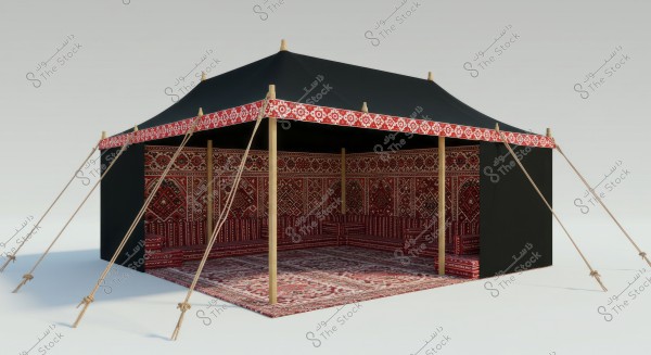 Image of a traditional Arabic tent, featuring wooden poles and ropes to support the structure. The tent is adorned with red and white decorative patterns along its edges. The interior is decorated with traditional red carpets and designs.