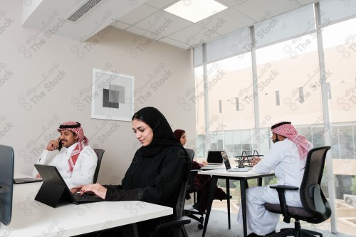 A group of Saudi employees working in the work hall during the day