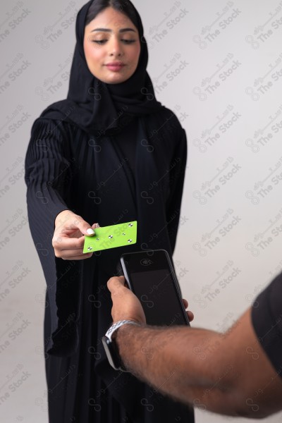 Portrait of a Saudi woman holding a card and making automatic payments on a white background