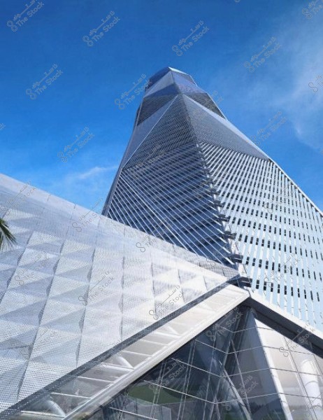 A view of a tall skyscraper from a tilted angle showcasing modern architecture against a clear blue sky. The facade features geometric metallic designs reflecting the light.
