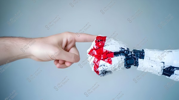 The image shows a human hand reaching towards a robotic hand, as if about to touch their fingertips. The robotic hand is composed of white and red parts, giving it a futuristic mechanical appearance. The background is light blue.