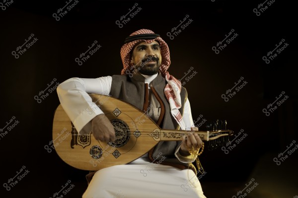 رجل عربي يرتدي الدشداشة والغترة يعزف على العود في إضاءة خافتة.
