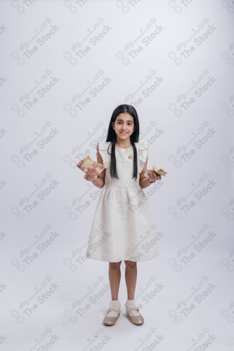 Portrait of a Saudi girl on a white background making gestures with her hands while smiling, souvenir photos, documenting a happy moment, Eid candy, Eid gifts, Eidiyat