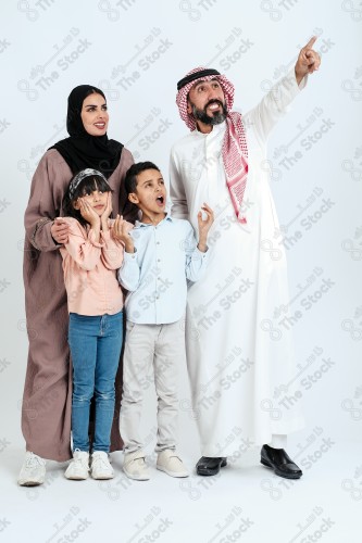 Portrait of a Saudi family looking towards a place, two children standing next to their parents pointing towards a goal, signs of happiness, a happy family atmosphere, the concept of a happy family, spending enjoyable family times