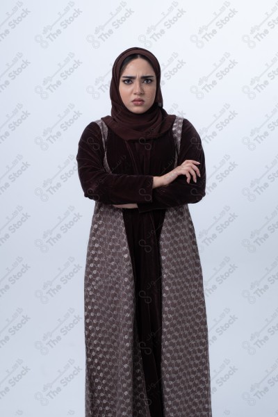 A young Saudi woman wearing an abaya and hijab, looking angry