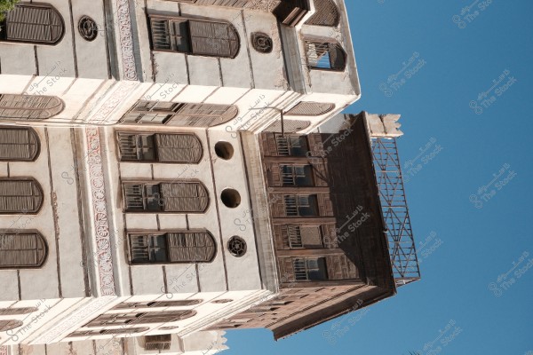 An old heritage building with ornate wooden windows under a blue sky.