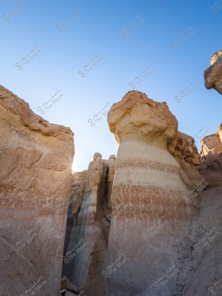 Large natural rock formations in a mountainous area under a clear blue sky, reflecting various shades of brown and beige with natural erosion effects.\r\n\r\n-