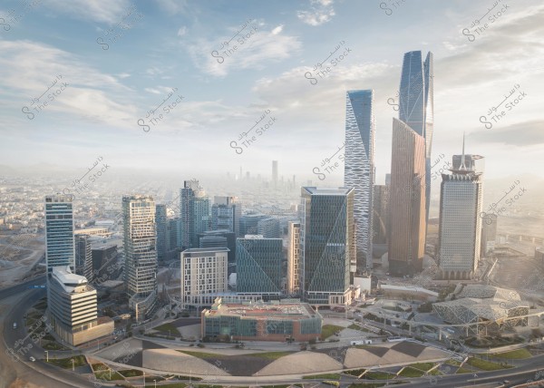 A view of a cluster of modern towers in Riyadh, Saudi Arabia. The image showcases skyscrapers of various designs and colors under a clear sky, with multiple-use buildings in the foreground and some winding streets around the structures.