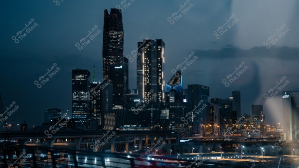 صورة لمدينة الرياض ليلًا تظهر فيها ناطحات السحاب والأضواء المضيئة والمتلألئة في السماء الزرقاء.