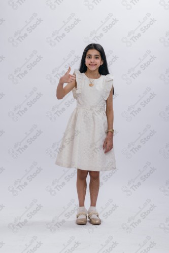 Portrait of a Saudi girl on a white background making gestures with her hands while smiling, souvenir photos, documenting a happy moment, Eid candy, Eid gifts, Eidiyat