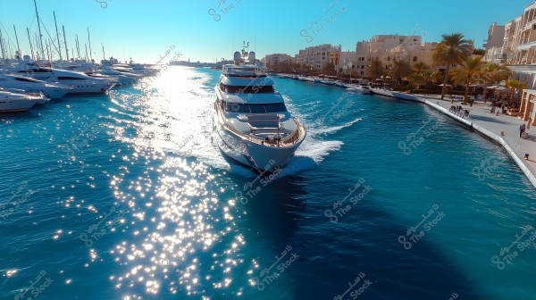 Image of a luxury yacht sailing through blue sea waters in a modern marina. Other yachts are docked on the left side of the image, with palm trees and residential buildings extending on the right. Sunlight reflects off the water\'s surface, creating a sparkling effect.