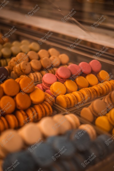 مجموعة متنوعة من حلوى الماكرون الملونة معروضة في واجهة زجاجية.