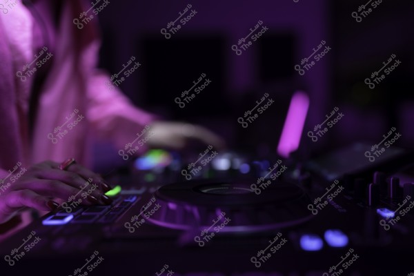 صورة لدي جي يعمل على جهاز تشغيل الموسيقى تحت إضاءة بنفسجية خافتة.