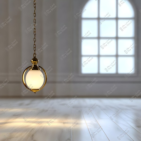 An image of a hanging golden lamp with a spherical glass, suspended from the ceiling of a spacious room. The floor is wooden, and there is a large arched window allowing daylight to enter the room, creating light reflections on the floor.