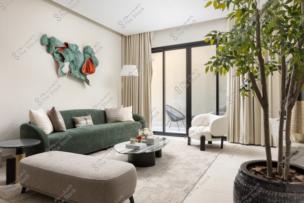 غرفة معيشة أنيقة تحتوي على أريكة خضراء وطاولة قهوة مع نباتات ديكورية, ولوحة فنية معلقة على الجدار.