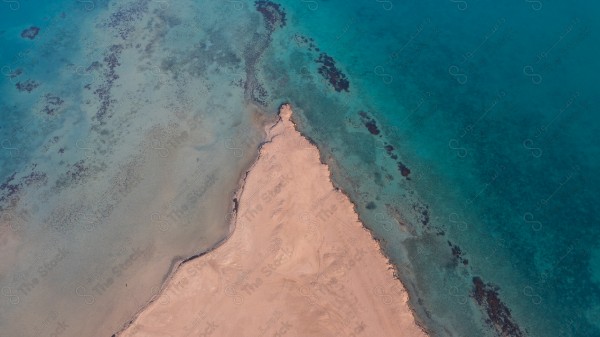 تصوير جوي لمنظر خلاب يبرز البحر الأزرق، يتوسطه امتداد ساحر من الرمال.