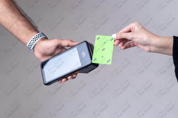 Portrait of a Saudi woman holding a card and making automatic payments on a white background