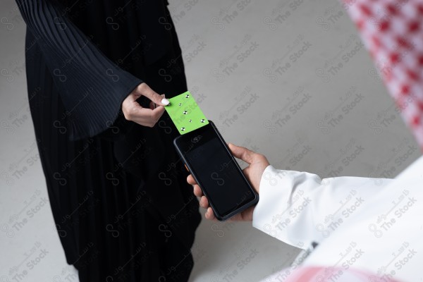 Portrait of a Saudi woman holding a card and making automatic payments on a white background