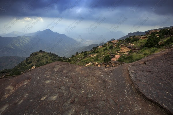 Aerial shot of a series of rocky mountains and the overlapping of clouds between them, nature in Saudi Arabia, the sky is clear