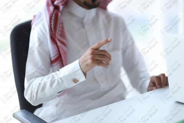 لقطة مقربة ليد رجل يرتدي الزي السعودي التقليدي وهو يشير بيدة، مناقشة حول العمل في غرفة الاجتماع نهارًا، اعمال