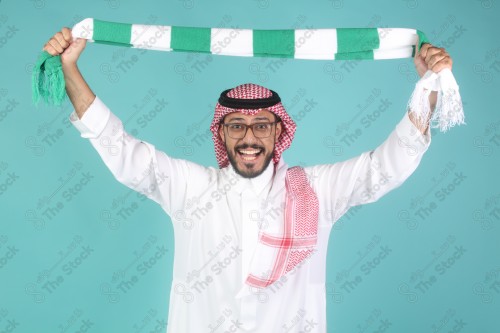 شاب سعودي يرتدي الزي السعودي ممسك شال بيده ويقوم بتعابير بوجه و يدينه تدل على السعادة والحماس ، كأس العالم ، المنتخب السعودي.