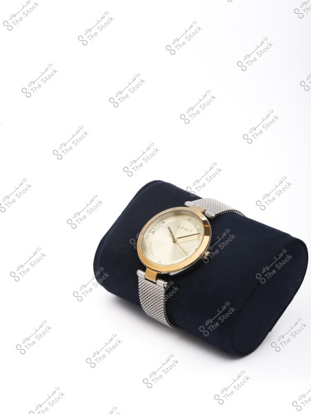 A stylish wristwatch with a gold face and silver strap displayed on a black cushion. The background is white.