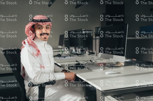 موظف سعودي يرتدي الثوب في العمل ويحمل اوراق بيديه.