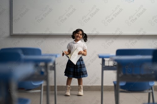 A Saudi student wears a school uniform and does different interactions and shows the tables in the classroom