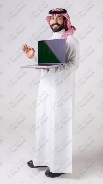 Portrait of a Saudi man holding a laptop, pointing at the laptop and making different expressions - green screen