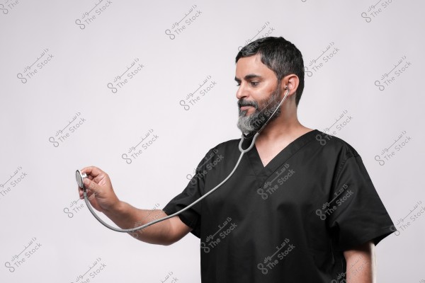 طبيب يرتدي مريولاً أسود يستخدم سماعة طبية على خلفية بيضاء.