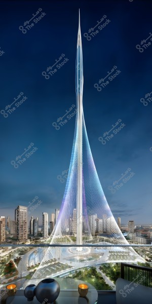 A nighttime image of a towering architectural structure in an urban setting. The tower has a futuristic design, illuminated with bright and vibrant colors including white, blue, and purple. Surrounding the tower are modern buildings with cityscapes underneath the evening lights. In the foreground, there is a balcony with a glass table featuring three decorative vessels lit by small yellow candles.