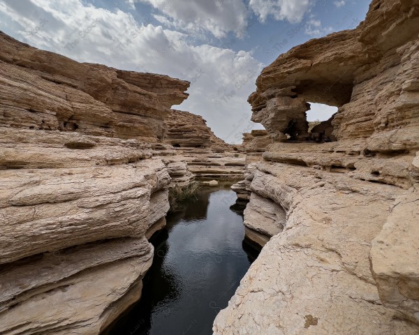 لقطة لاحد الاودية لسلسلة جبال طويق في منطقة نجد وتظهر السماء شبه غائمة ، سلسلة من الجبال الصخرية ، تكوينات صخرية.