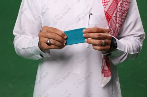 رجل سعودي على خلفية خضراء يحمل ببطاقة الصرافة مستعد للتسوق