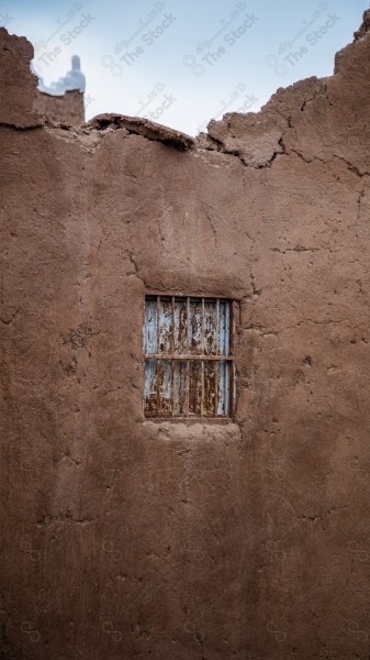 The picture shows a mud building in the heritage villa in Ushaiqar, characterized by an old window, while the clear sky lives behind it.