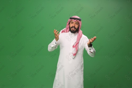 رجل سعودي يقف على خلفية خضراء يرتدي الثوب و الشماغ، يقوم بعمل حركات بيديه ، احتفالات العيد