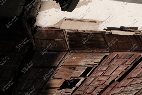 Old, weathered wooden doors attached to a wall of an aged building with a rusty, vintage look.