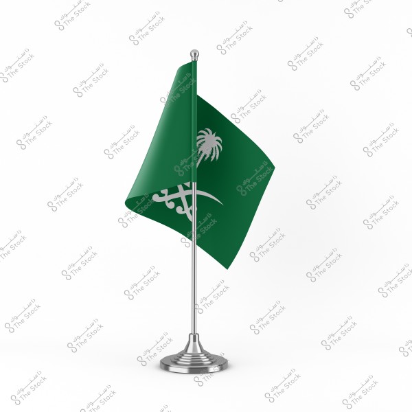 An image of the flag of Saudi Arabia placed on a silver stand. The flag is green with a white sword and the Islamic declaration of faith in white. The background is completely white.