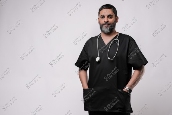 طبيب يرتدي زي طبي أسود مع سماعة طبية حول رقبته ويبتسم أمام خلفية بيضاء.