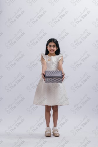 Portrait of a Saudi girl on a white background making gestures with her hands while smiling, souvenir photos, documenting a happy moment, Eid candy, Eid gifts, Eidiyat